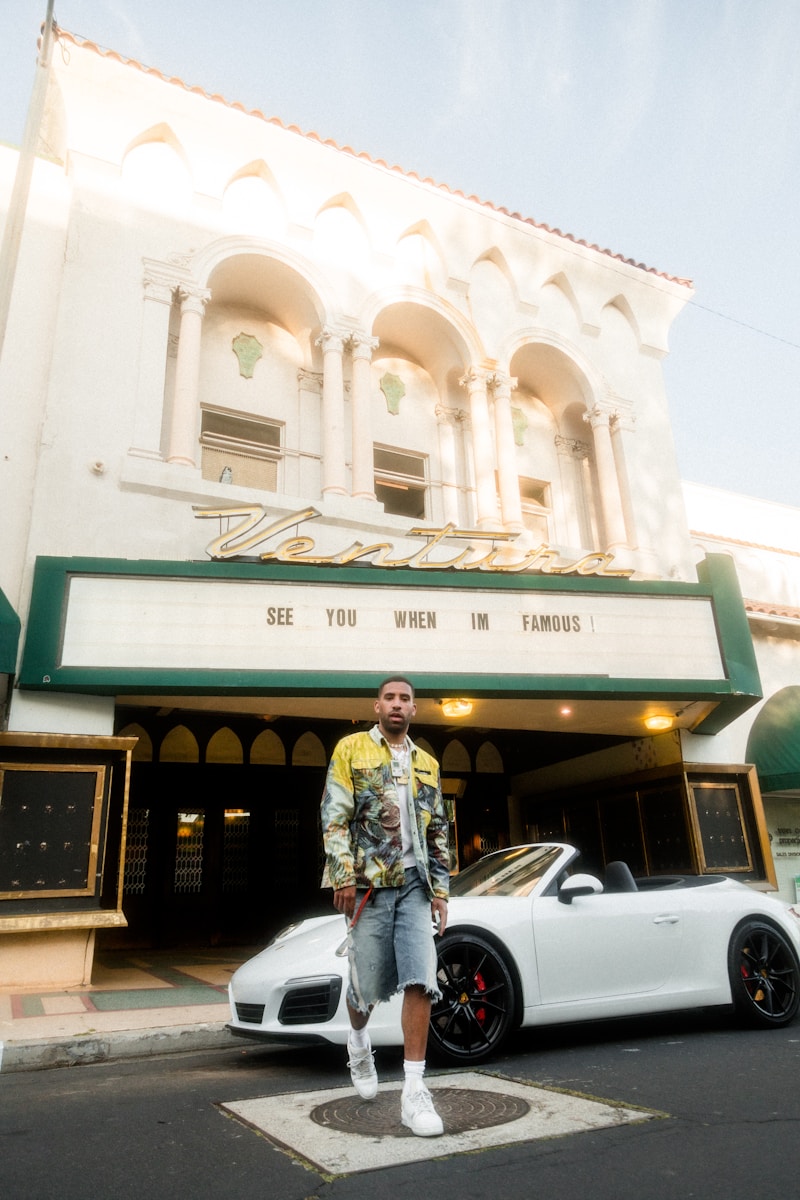 man in gray jacket standing beside white car during daytime